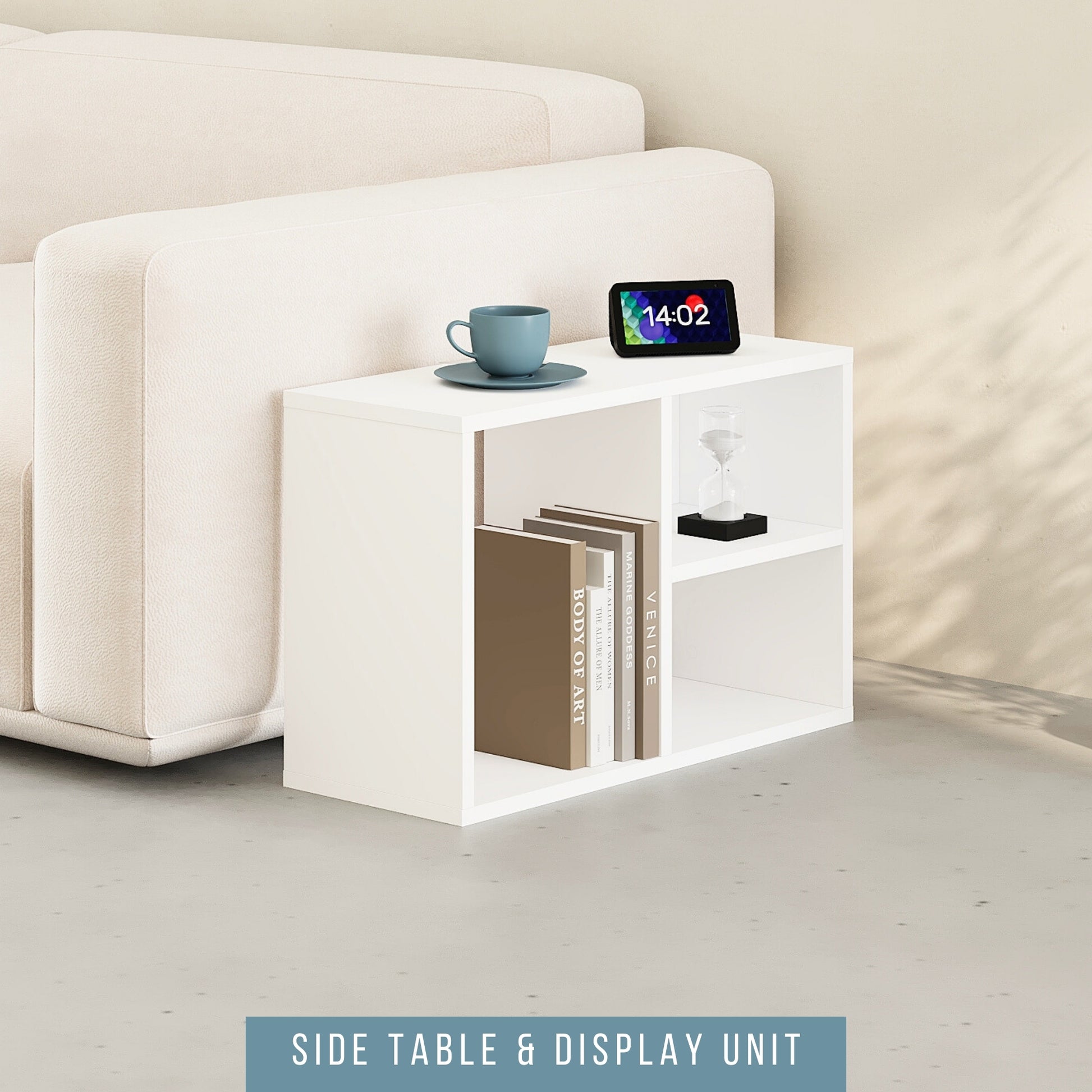 A white modular shelving unit placed next to a sofa, functioning as a side table with a cup on top and a display unit with a framed picture and books.